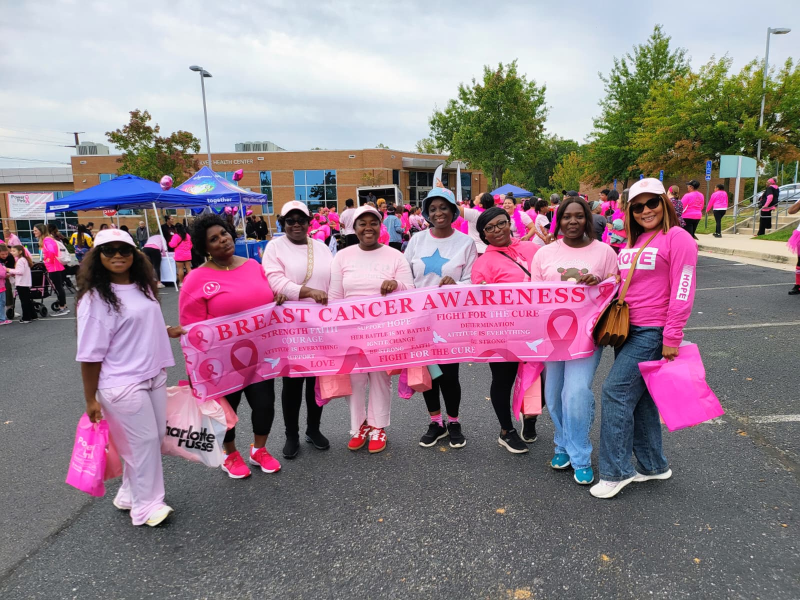 Church members in pink holding a breast cancer awareness banner at a community event